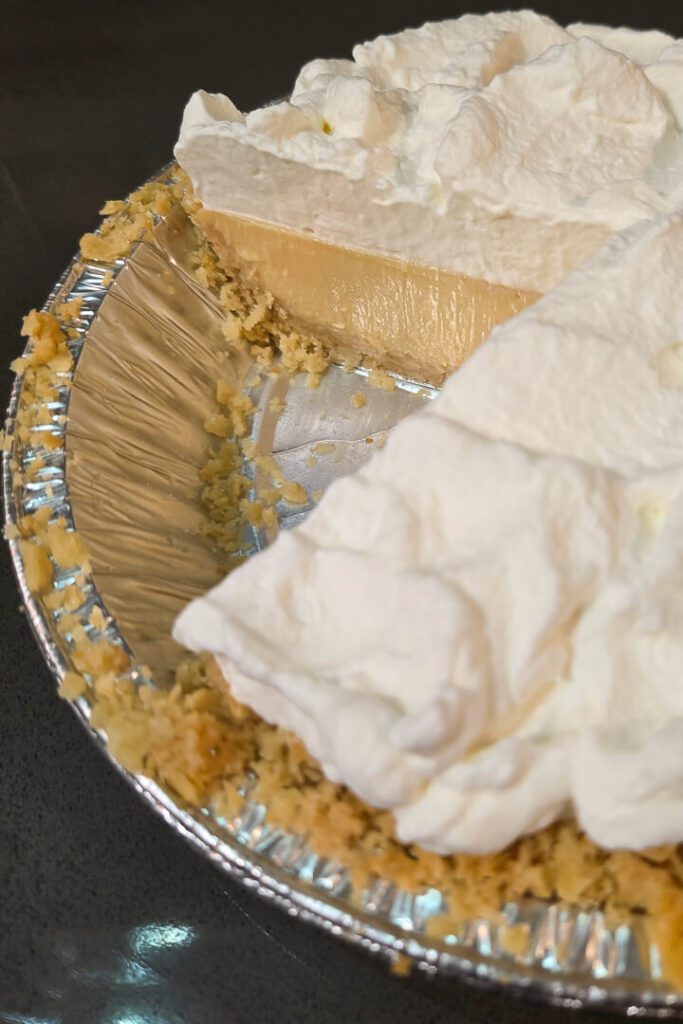 Atlantic Beach Pie with a slice cut out showing a clear cross section with whipped cream topping, saltine cracker crust, and whipped cream topping in an aluminum pie tin