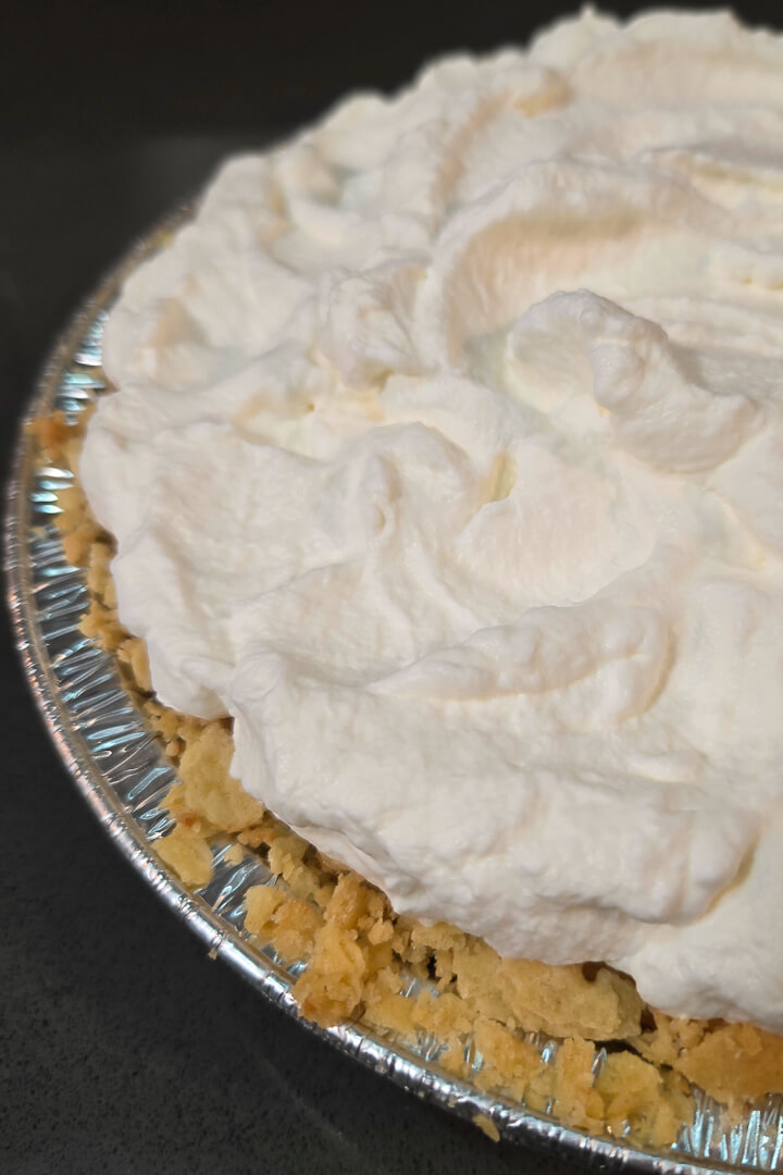 Atlantic beach pie recipe featured image showing a close up photo of a pie in a saltine cracker pie crust topped with whipped cream in a metal pie tin