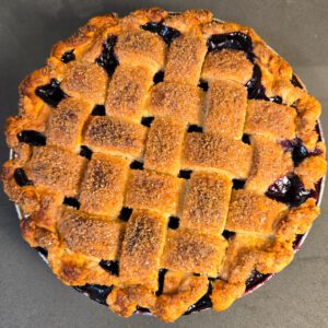 overhead photo of a blueberry pie topped with a lattice crust and crimped edges