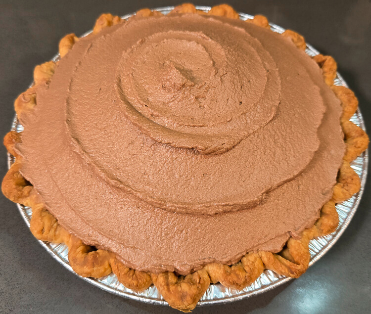 a close up photo of a whole chocolate mousse pie with a swirled design made with an offset spatula