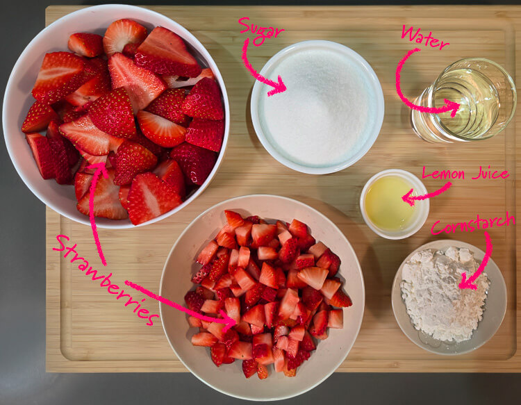 ingredients for fresh strawberry pie with homemade strawberry glaze laid out on a cutting board with text labels: strawberries, sugar, water, lemon juice, cornstarch