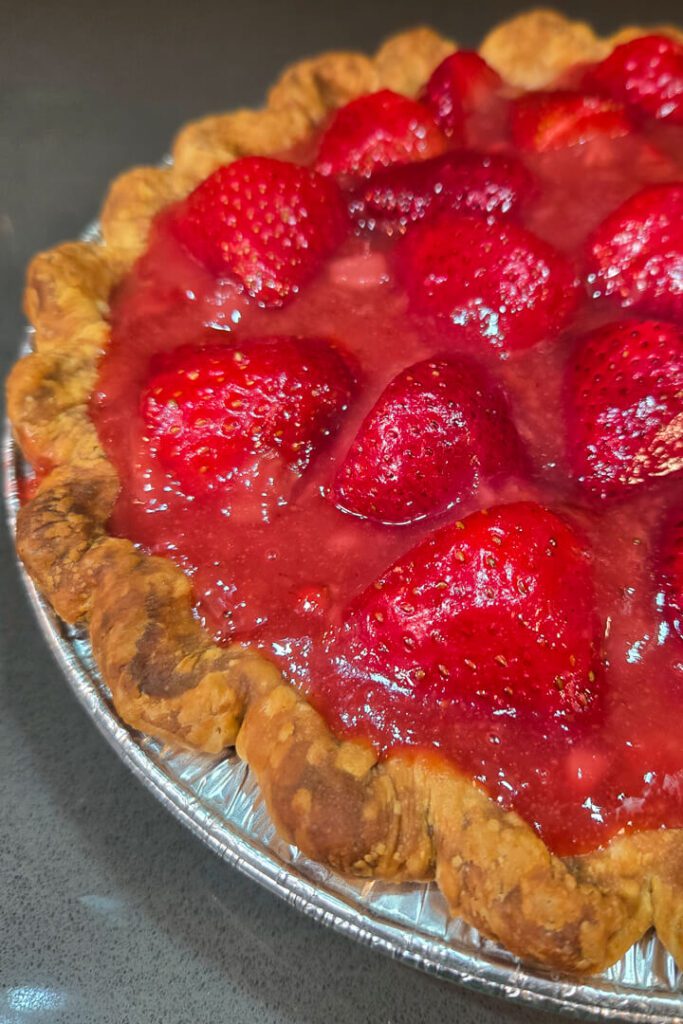 close up photo of a fresh strawberry pie with strawberry glaze in a crimped pie crust