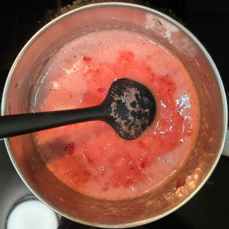 overhead photo of of a process photo of strawberry glaze being made on a stovetop