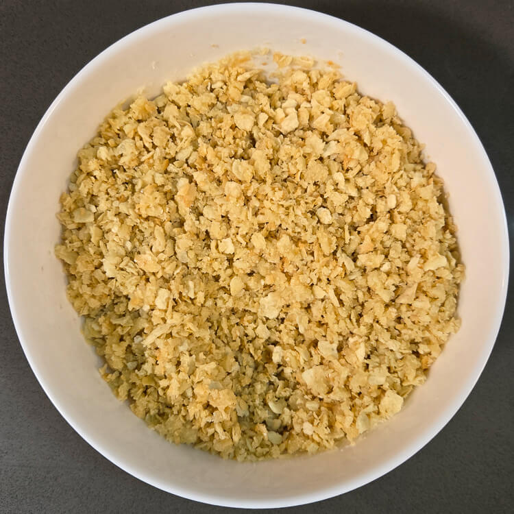 saltine cracker pie crust mixed in a white bowl before being pressed into a pie tin