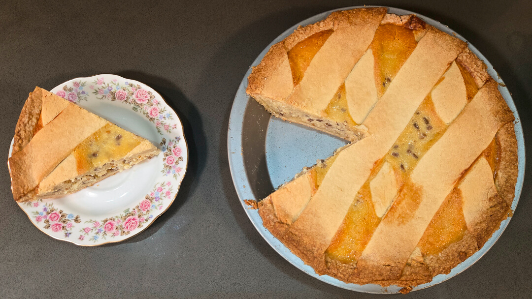 Pastiera napoletana with a slice cut out and placed next to it on a floral plate