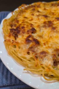 close up photo of a spaghetti pie in a white pie plate with a blue towel