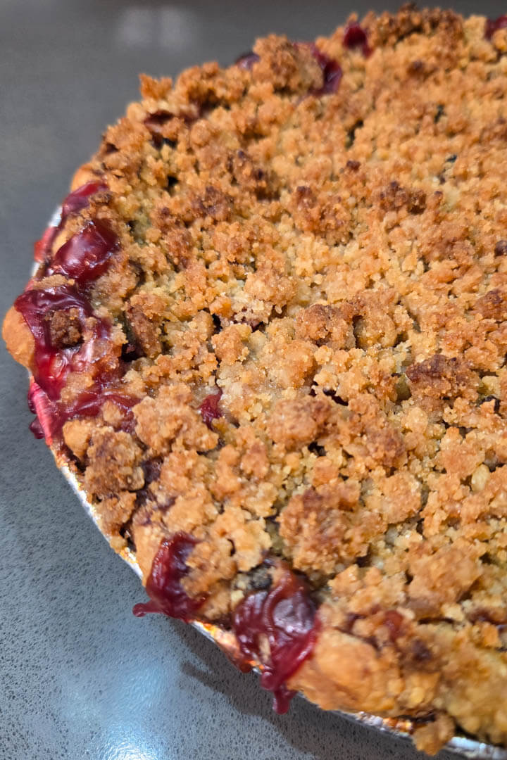 cherry rhubarb pie recipe. Close up photo of a cherry rhubarb pie with a crumb topping