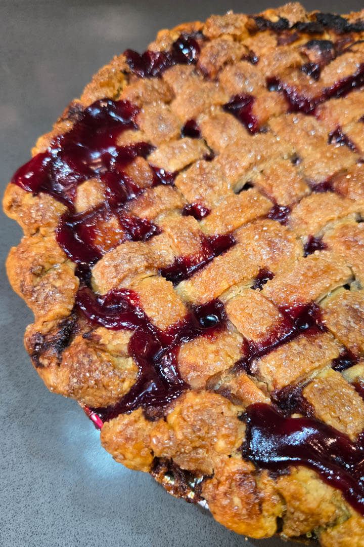 cherry pie recipe: a close up photo of a baked homemade cherry pie with a golden skinny lattice top