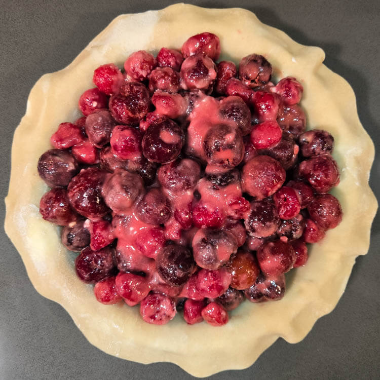 an overhead photo of cherry pie filling in a pie tin lined with pie dough