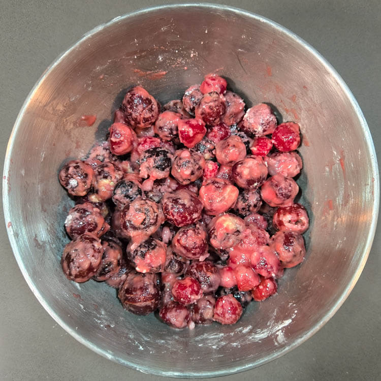 an overhead photo of homemade cherry pie filling being mixed in a mixing bowl