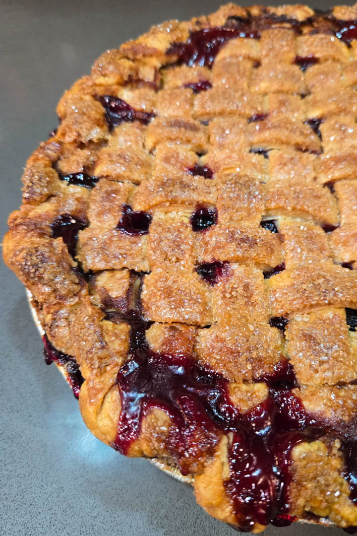 a close up photo of a baked homemade cherry pie with a golden skinny lattice top