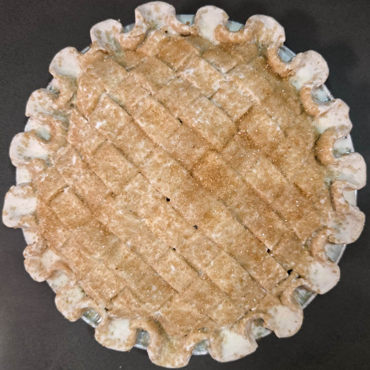 an overhead photo of a pie with a skinny lattice top before being baked