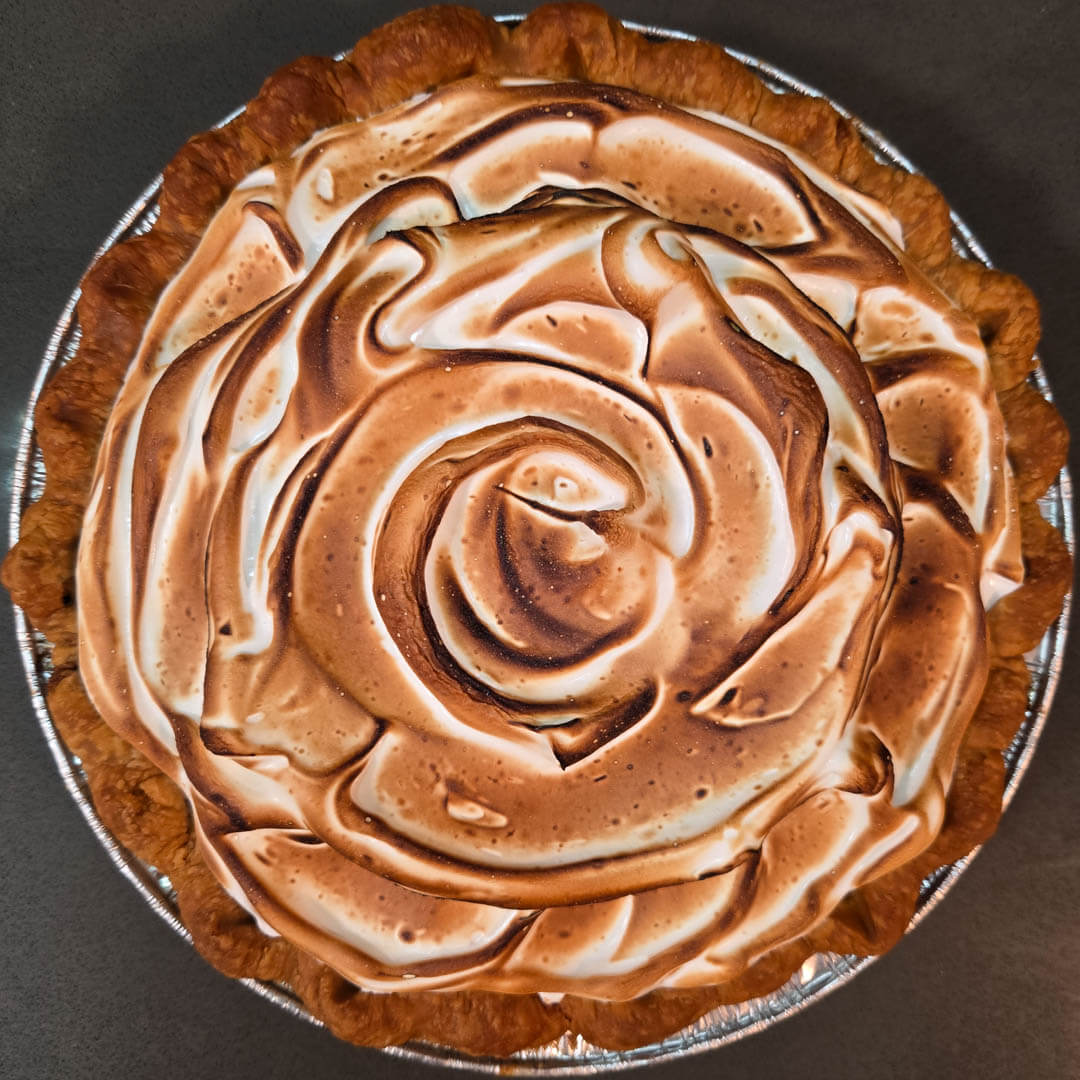overhead photo of a grapefruit meringue pie with toasted meringue topping in a crimped flaky pie crust