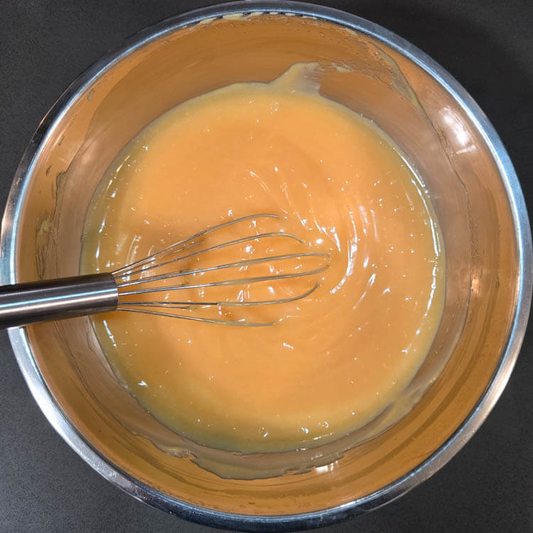 fresh grapefruit curd in a metal mixing bowl with a metal whisk