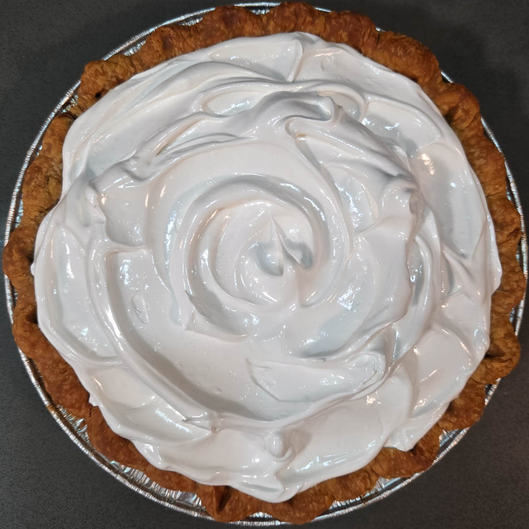 overhead photo of a grapefruit meringue pie with meringue topping that has not been toasted yet in a crimped flaky pie crust