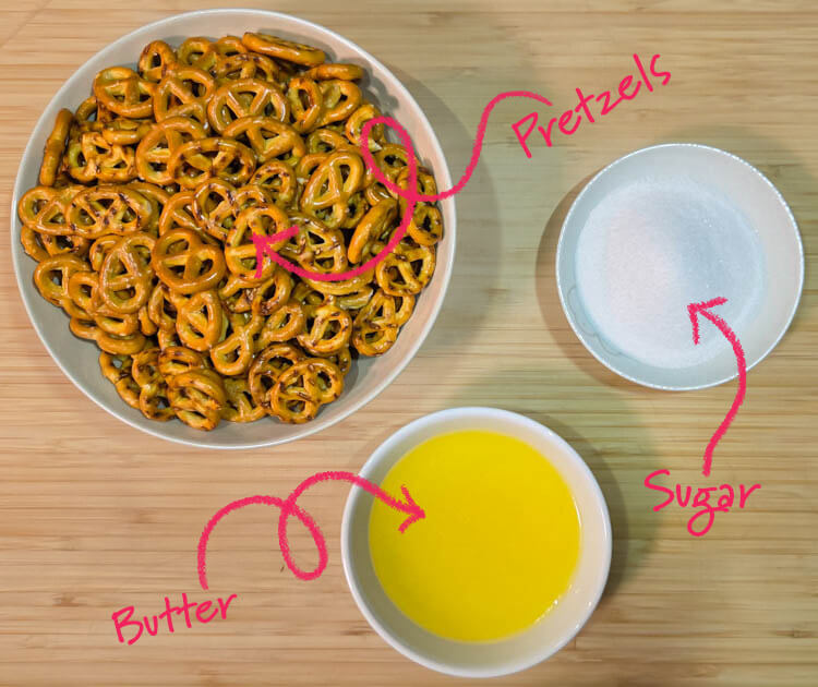 ingredients for a pretzel crust laid out on a cutting board with text labels: pretzels, sugar, and butter