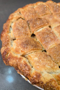 a close up photo of a golden brown apple pie with a crispy lattice top