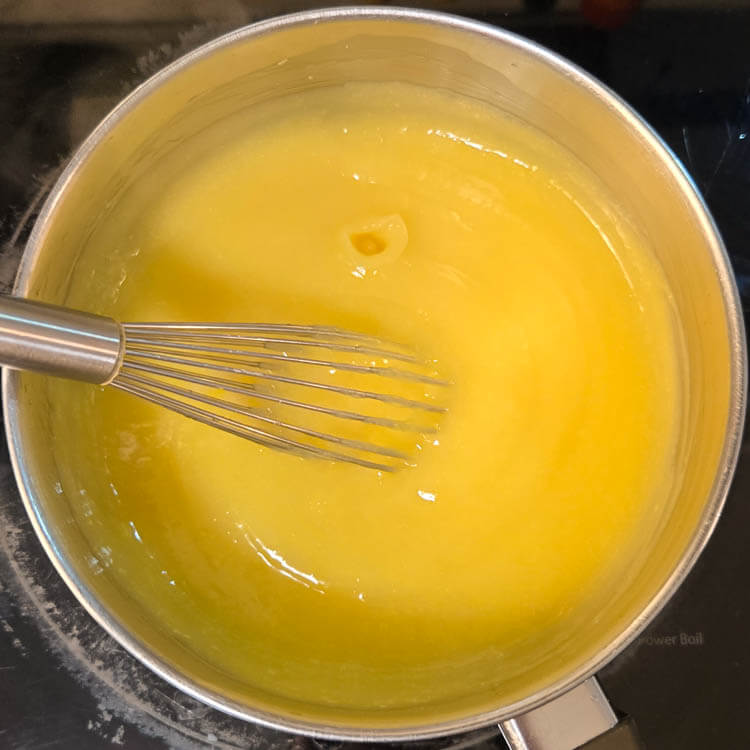 lemon curd being made on a stovetop with a metal whisk