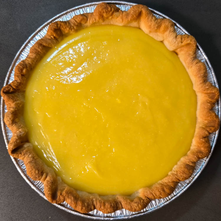 lemon meringue pie before being topped with meringue, showing homemade lemon curd in a golden flaky pie crust