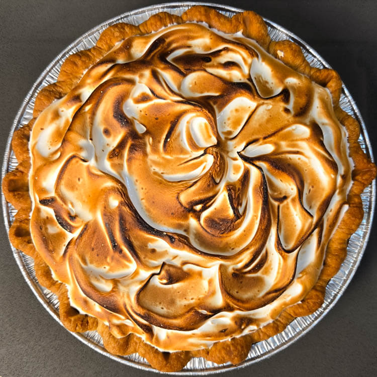 lemon meringue pie with swirls of toasted meringue in a crimped flaky pie crust