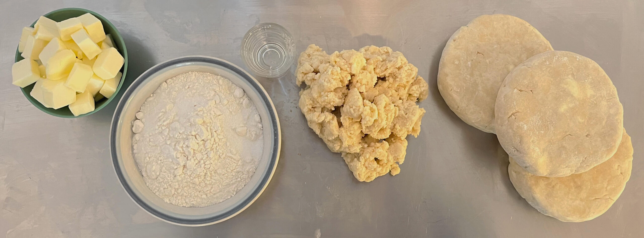 pie dough mixed in different stages: cubed butter, flour, water, mixed dough, and pressed pie dough