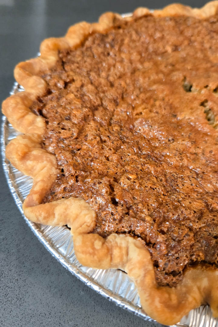 a close up photo of an old-fashioned oatmeal pie or nut free pecan pie in a crimped flaky pie crust