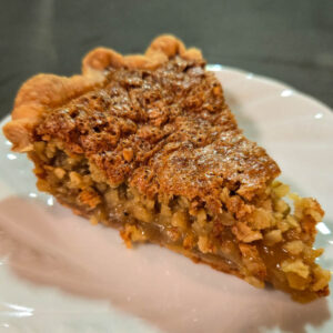a slice of Amish oatmeal pie on a white plate in a crimped flaky pie crust