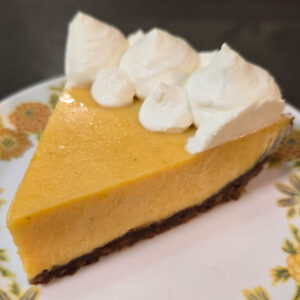 a slice of passionfruit pie on a white plate with yellow flowers topped with whipped cream swirls