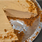 A cookie butter pie with a creamy, smooth cookie butter cheesecake filling in a Biscoff cookie crumb crust, with a slice being lifted out revealing the thick, rich filling. Text overlay reads "Cookie Butter Pie, Extra Easy No-Bake Dessert Recipe!" with the Doggone Baking logo and tagline "everything pie."